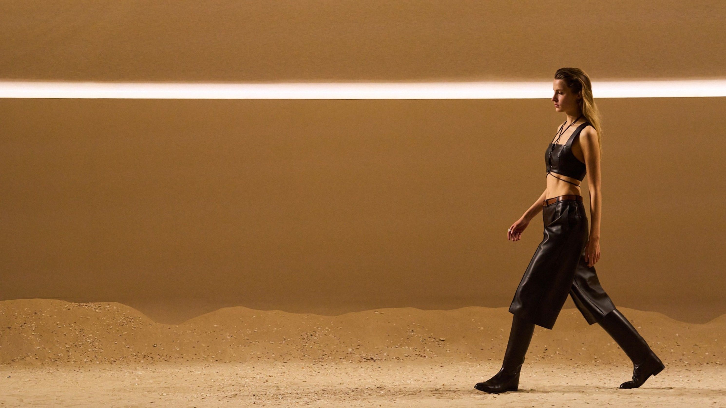 
Nella collezione Primavera/Estate 2026 di Hermès, bermuda in pelle color testa di moro scendono sotto il ginocchio, accompagnando crop top con spalline larghe ed unendosi a stivali equestri modello “Jumping”, per look che uniscono eleganza e comodità - Credits: Launchmetrics.com/Spotlight