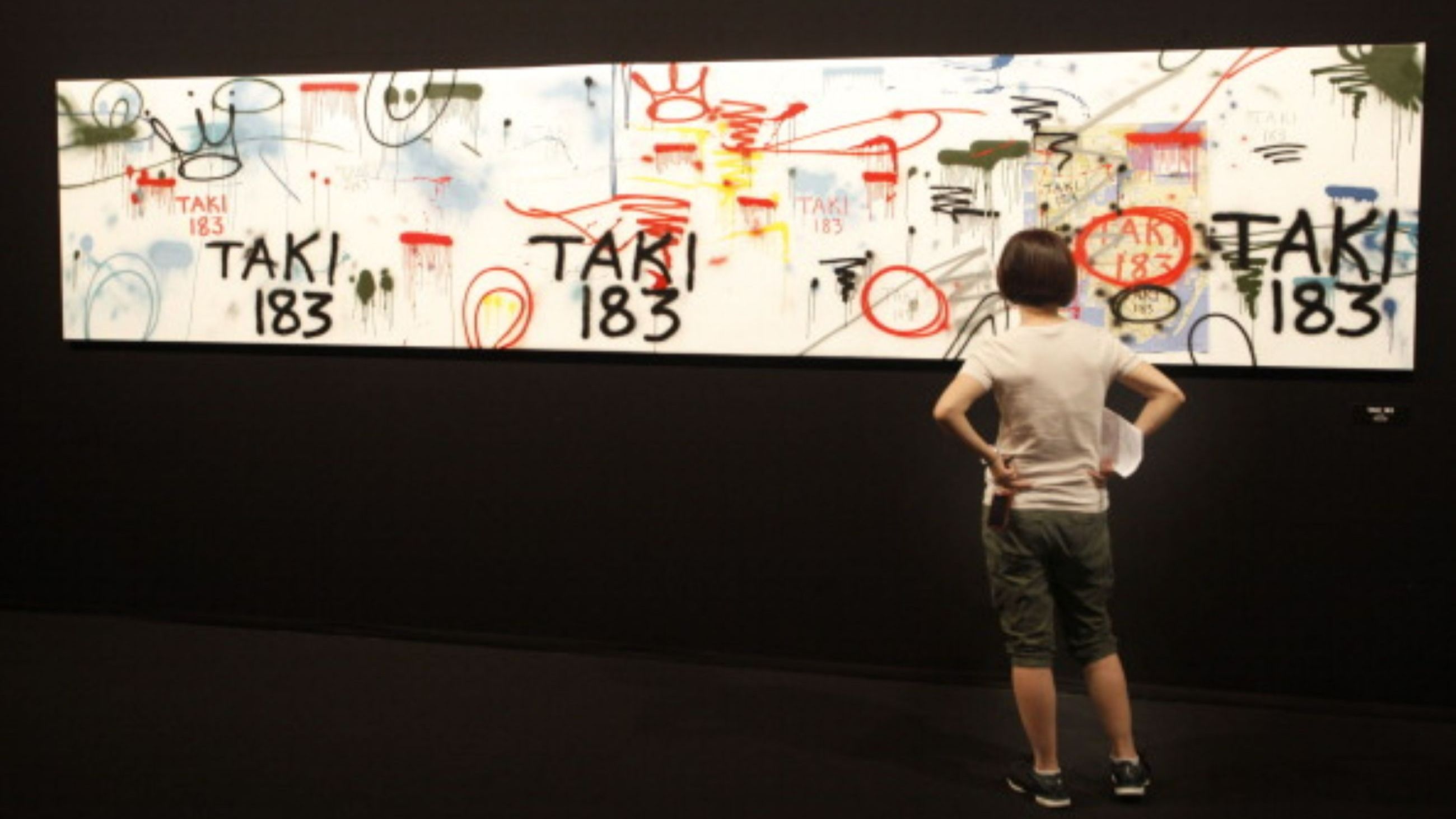 Una visitatrice osserva le opere di Taki 183 alla mostra “The Birth of Pressionism”, allestita al Grimaldi Forum di Monaco il 1° agosto 2011, in occasione del 40° anniversario del Graffiti Movement - Credits Getty Images