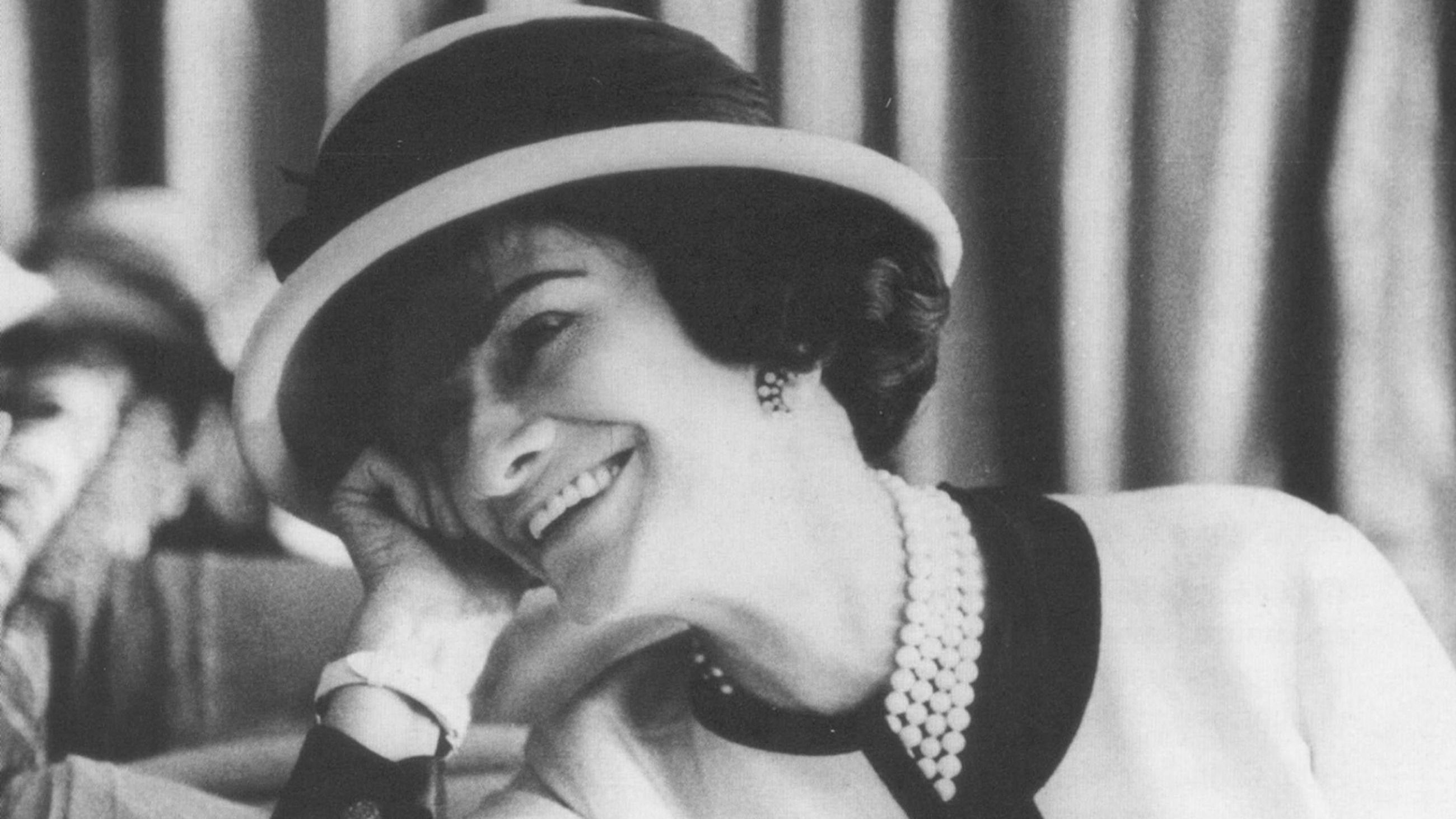 Gabrielle Chanel sorride con indosso un abito bianco dai profili neri. Il "non colore" per eccellenza non mancava e non manca nelle collezioni Chanel, in un gioco elegante con il nero - Credits: Ufficio Stampa