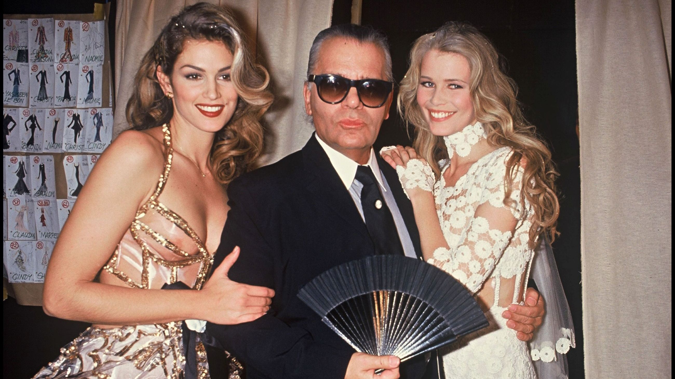 Cindy Crawford insieme allo stilista Karl Lagerfeld e a Claudia Schiffer, altro volto iconico del fashion system, nel backstage della sfilata di Chanel, 1993 - Credits: Getty Images