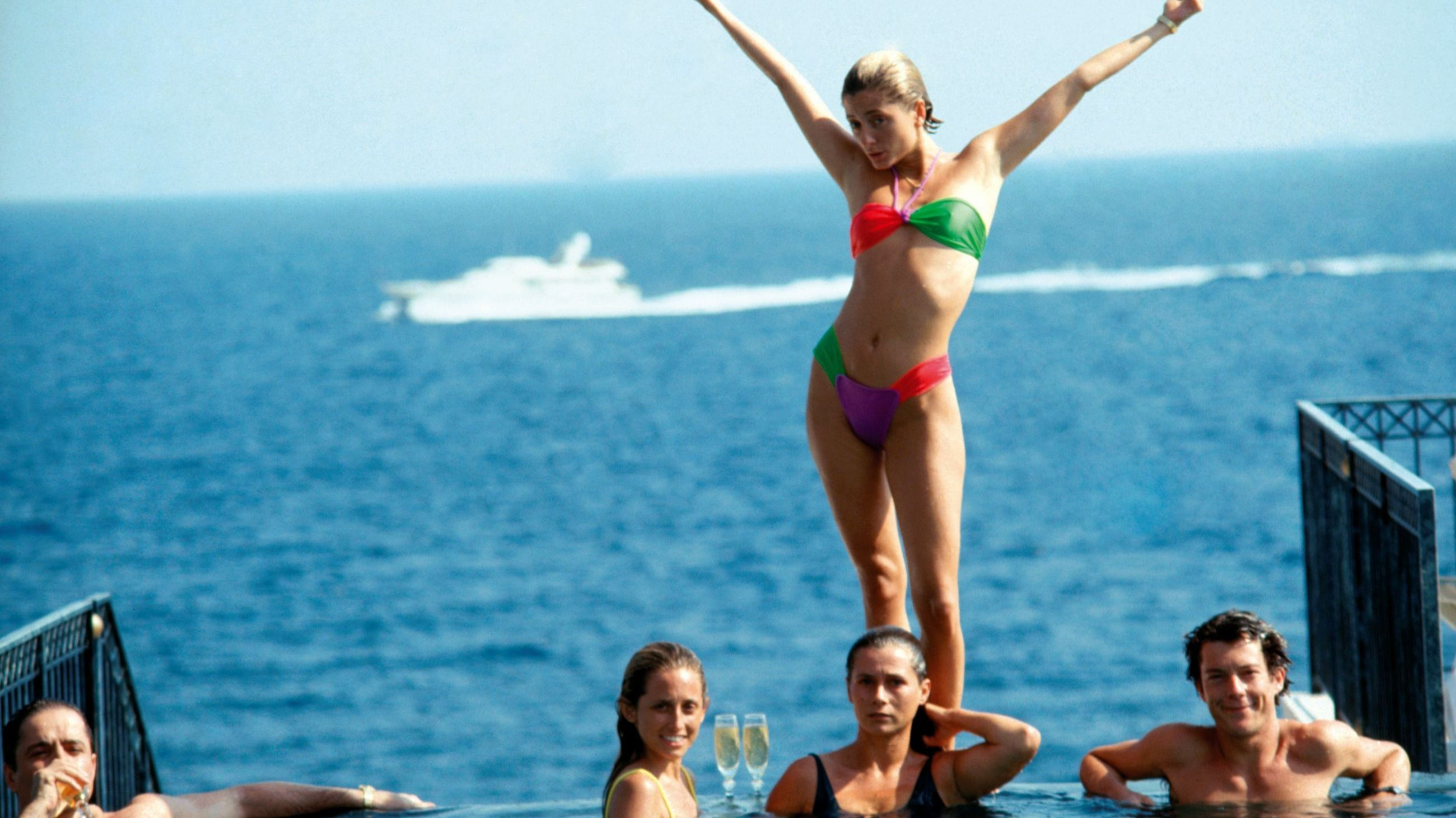 Marie-Chantal Miller, futura moglie del principe Pavlos di Grecia, posa in modo stravagante sopra la sorella Pia (in giallo), che sta per sposare Christopher Getty. Le due sono adagiate nella piscina dell'Hotel Belair, a Cap Ferrat, nel luglio del 1991 - Credits: Getty Images