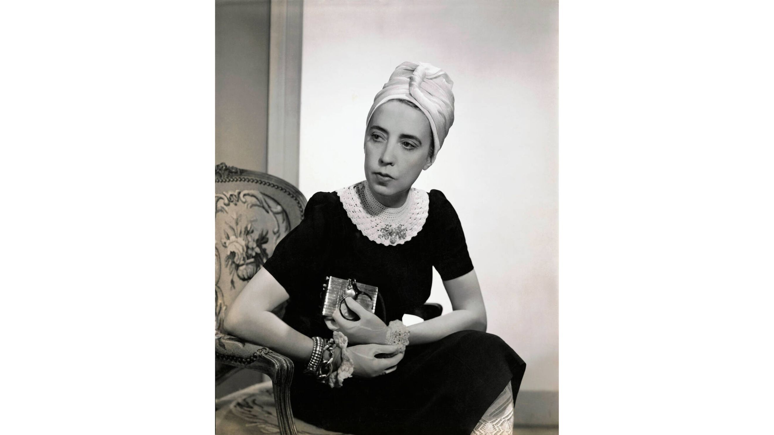 La stilista Elsa Schiaparelli indossa un abito di seta nera con colletto all'uncinetto di sua creazione e un turbante; fotografia di Fredrich Baker, Vogue, 1940 © Condé Nast via Getty Images 