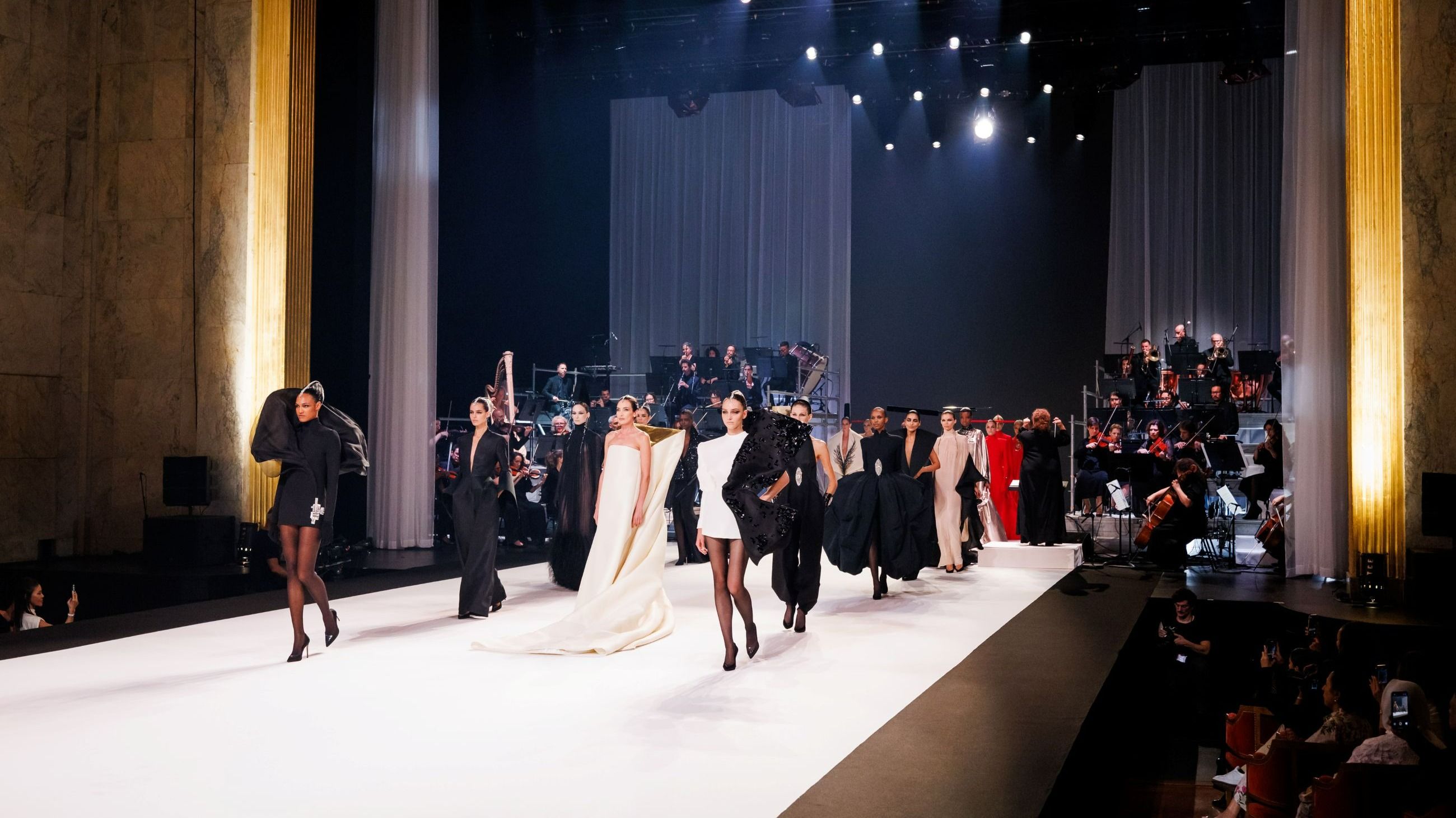 Le modelle sfilano in passerella mentre Zahia Ziouani e la sua orchestra si esibiscono durante la sfilata Stéphane Rolland Haute Couture Autunno/Inverno 2025/2026 al Théâtre des Champs-Élysées, nell’ambito della Paris Fashion Week, l’8 luglio 2025 a Parigi, Francia - Credits: Getty Images