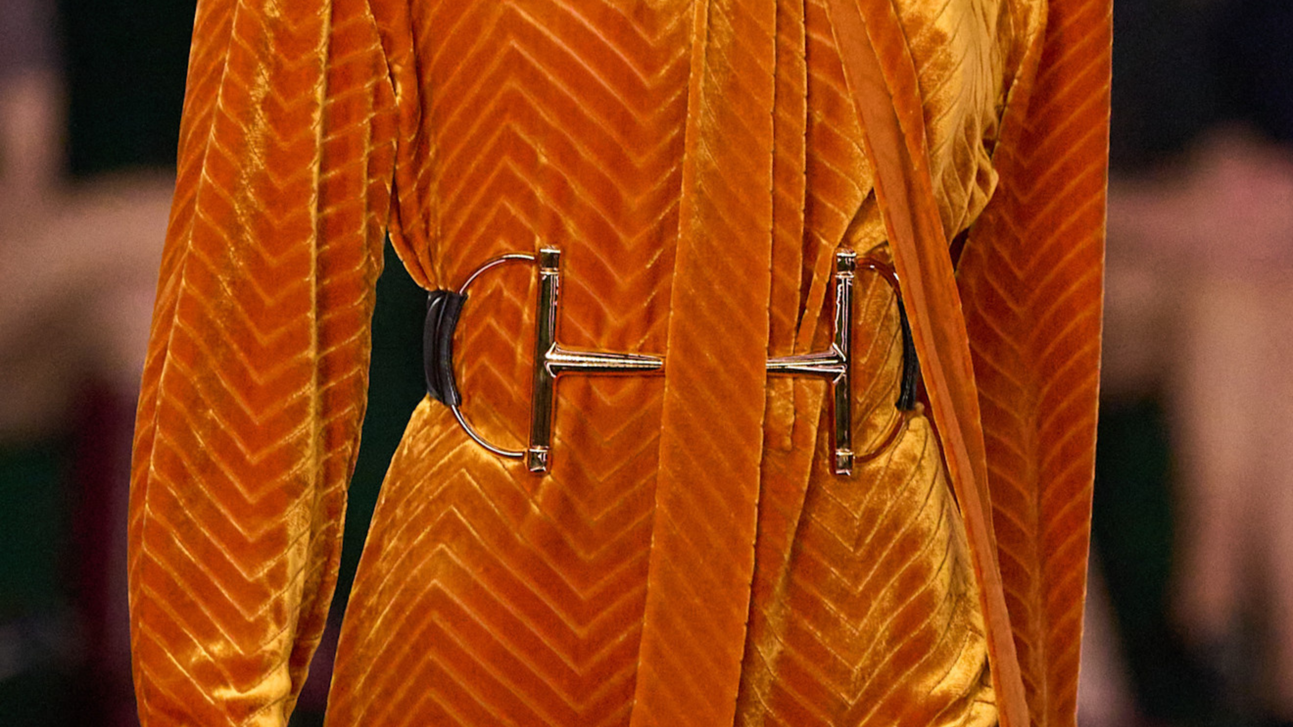 Cintura a forma di filetto equestre, simbolo iconico della casa di moda Gucci, che segna il punto vita e da ancora più luce a un abito longuette in velluto color arancione della collezione Gucci FW2526 - Credits: Launchmetrics.com/Spotlight