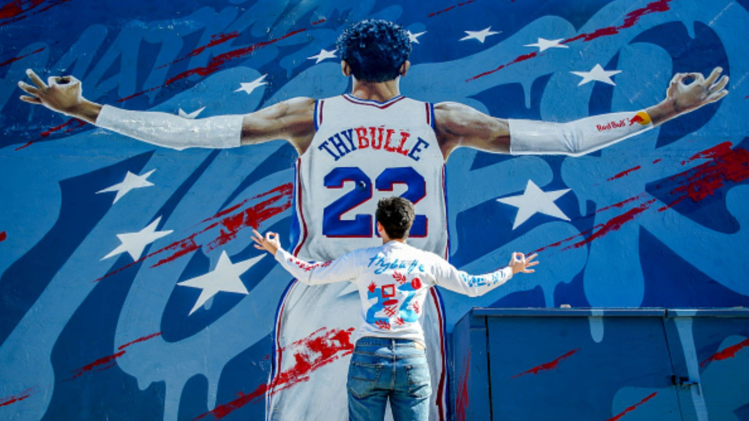 Lucas Wallick posa davanti al murale dedicato a Matisse Thybulle, realizzato dall’artista Gloss Black nel quartiere di Fishtown e presentato il 5 marzo 2021 grazie a una collaborazione tra il giocatore, i 76ers e Red Bull - Credits Getty Images