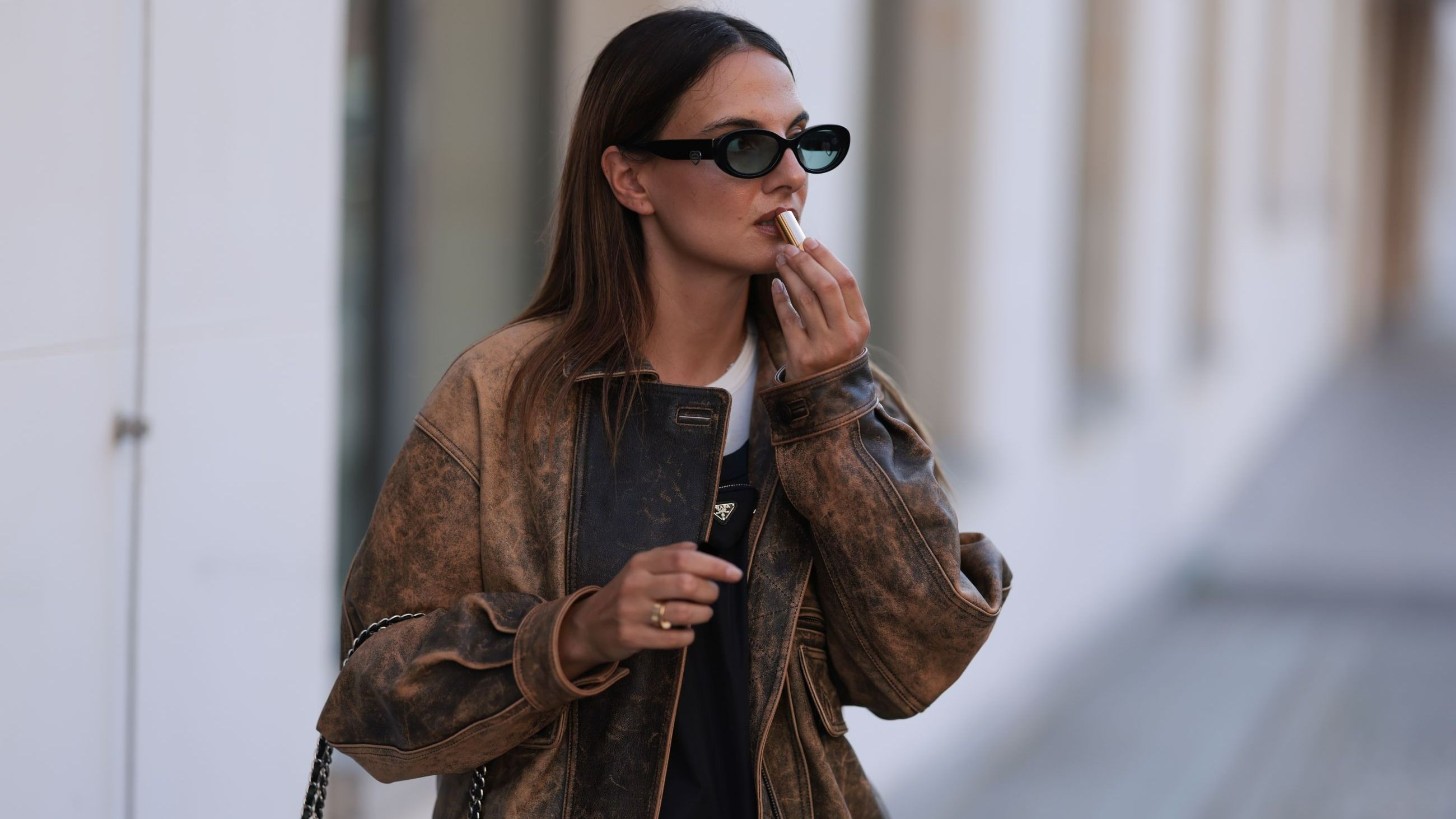 Anna Winter indossa occhiali da sole neri di Tiffany & Co, una camicia bianca in cotone basic di Weekday, un mini abito nero in nylon con logo di Prada, un bomber oversize in pelle marrone sbiadita di Source Unknown, una borsa a tracolla in pelle nera di Chanel e un rossetto / balsamo labbra di Chanel, il 29 agosto 2024 a Berlino - Credits: Getty Images