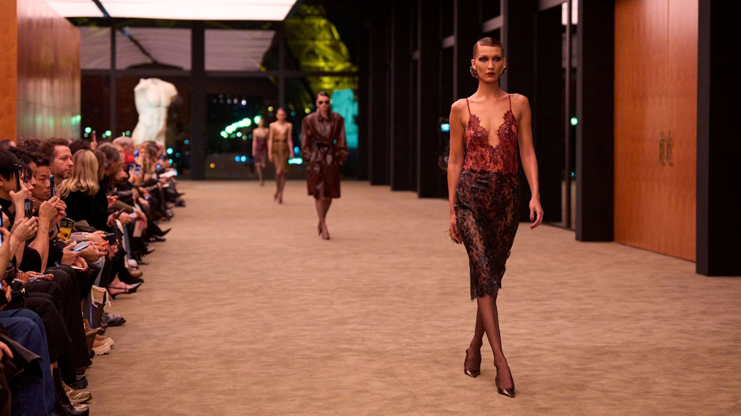 Dalla sfilata FW26-27 di Saint Laurent: in primo piano, a destra, la top model Bella Hadid, che indossa una mise in pizzo, materiale tra i protagonisti di questa collezione - Credits: Launchmetrics.com/Spotlight