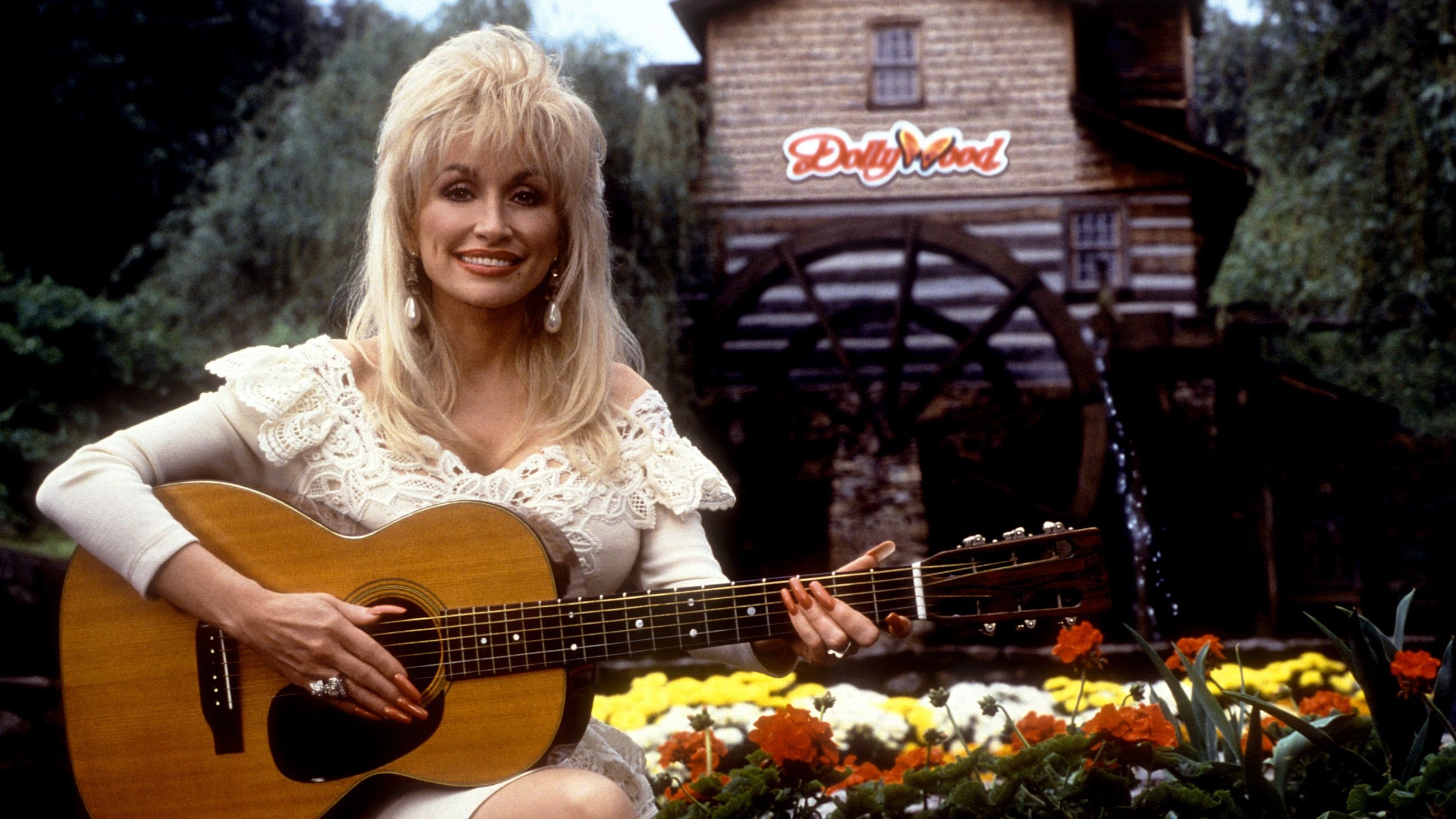 La cantante e cantautrice americana Dolly Parton posa per un ritratto con la sua chitarra a Dollywood, intorno al 1993, a Pigeon Forge, Tennessee - Credits: Getty Images
