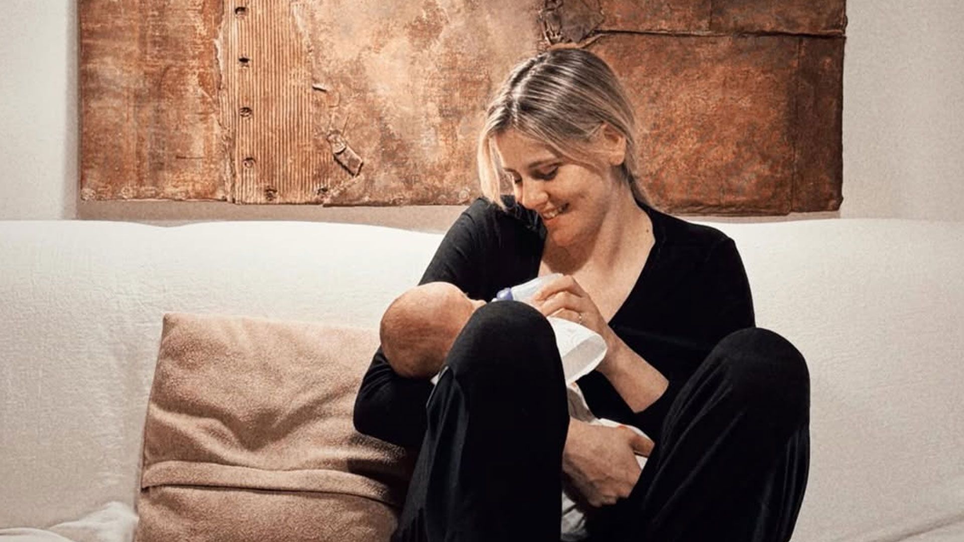 Arianna Montefiori seduta sul divano mentre tiene teneramente in braccio la figlia Allegra | Instagram: @brigaofficial