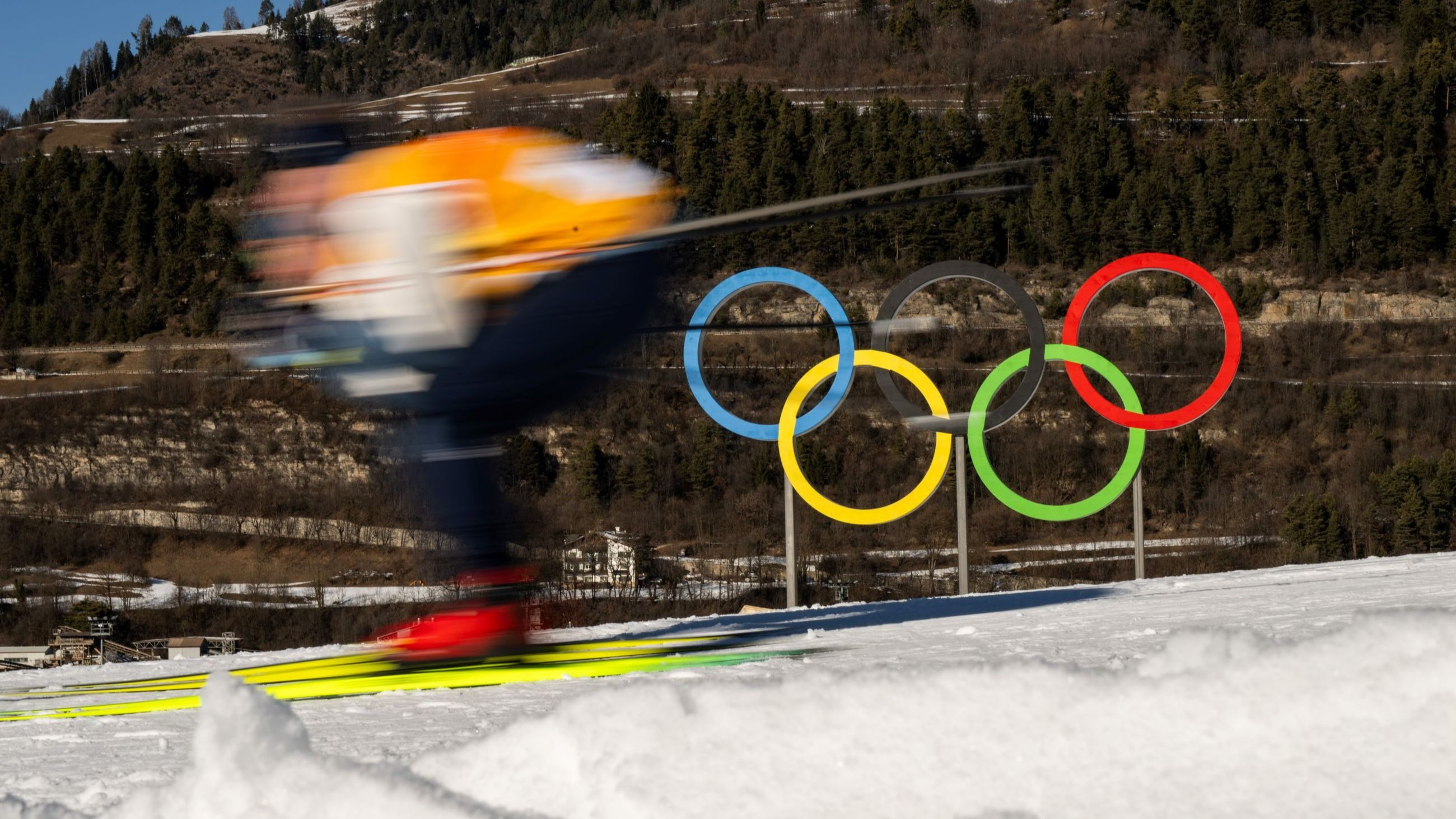 Olimpiadi invernali Milano Cortina 2026, nella foto uno sciatore sfreccia davanti agli anelli olimpici - Credits Agf