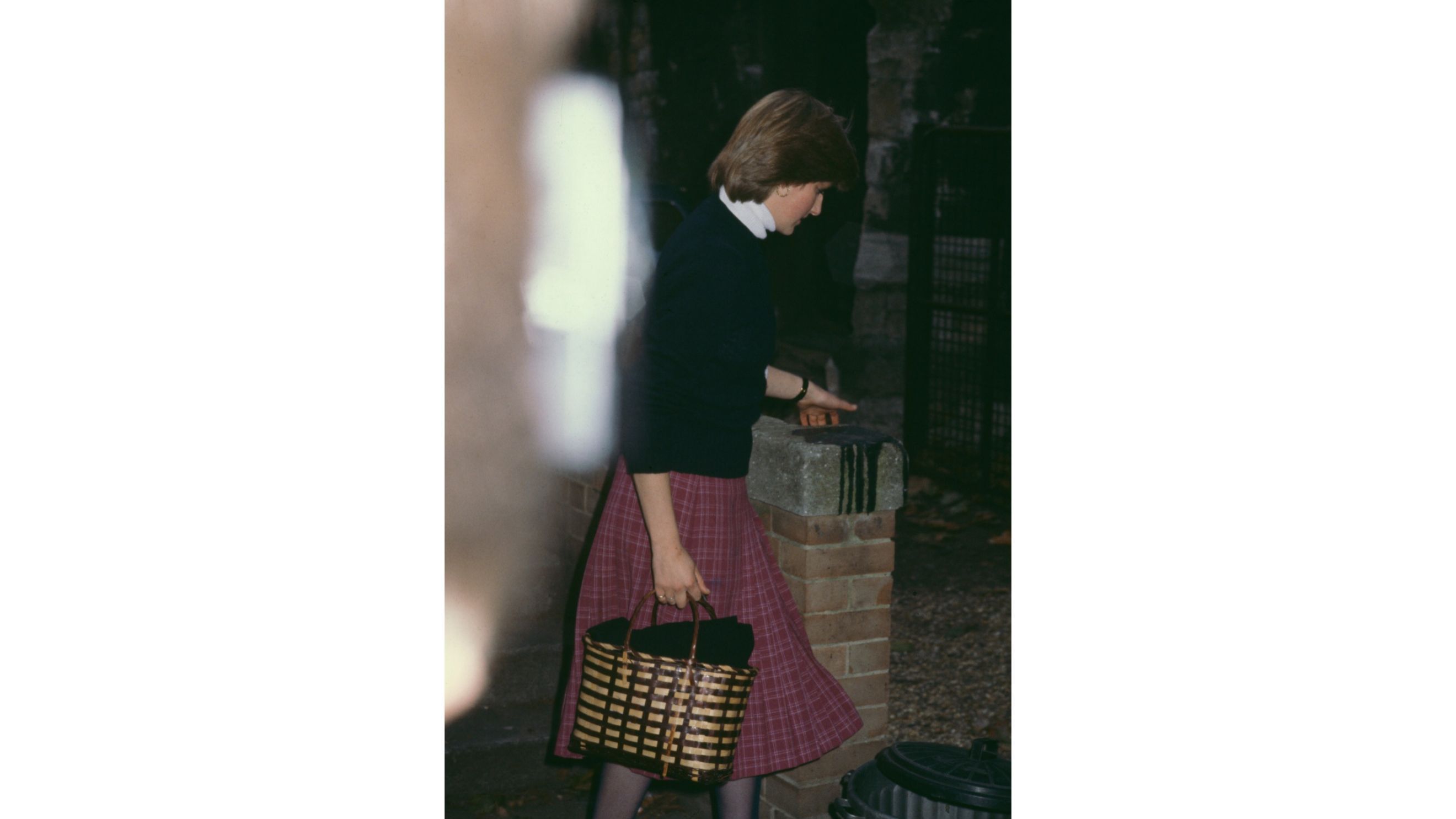 Lady Diana Spencer (1961-1997), membro della famiglia reale britannica, indossa un maglione scuro e una gonna a quadri rosso scuro e porta una borsa marrone mentre esce dalla scuola materna Young England Kindergarten, nel quartiere di Pimlico, a Londra, in Inghilterra, nell’ottobre del 1980. Diana lavora presso la scuola come assistente di un’insegnante d’asilo - Credits: Getty Images
