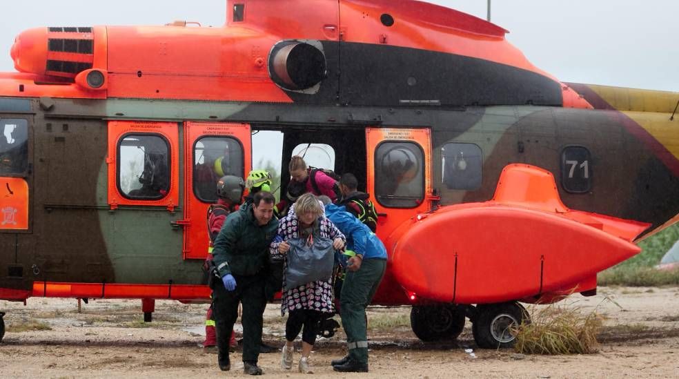 Varias personas se bajan de un helicóptero de los servicios de emergencia tras ser rescatados este lunes en la localidad de Oliva