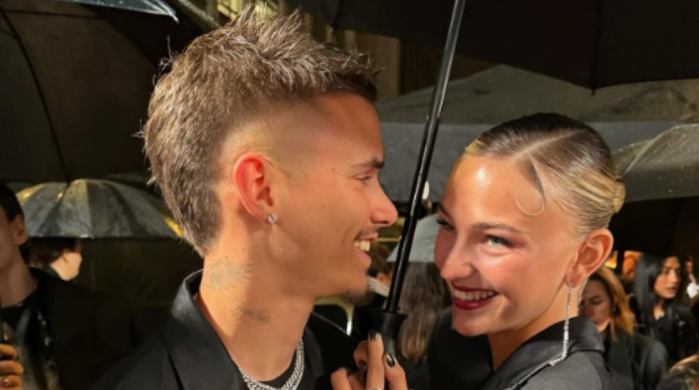 Romeo Beckham y Mia Regan juntos bajo paraguas en un evento