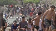 Familias enteras de inmigrantes llegan a la playa con flotadores y otros cruzan directamente el espigón